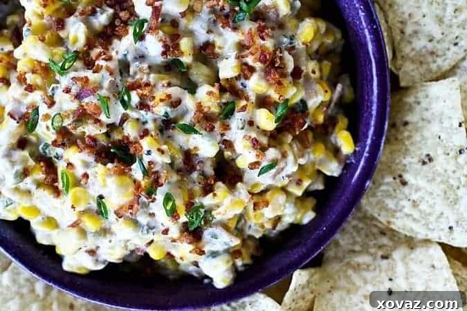 A vibrant close-up of the Slow Cooker Spicy Bacon Corn Dip in a white serving bowl, with a large serving spoon ready to scoop, surrounded by golden tortilla chips.