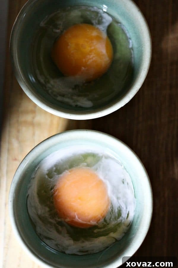 Close-up of an egg cracked into a ramekin after the 10-second shell blanch, showing the slightly set whites.