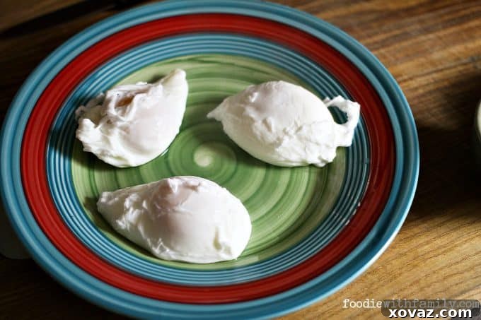 Two beautifully formed poached eggs in a pot, demonstrating the effectiveness of the blanching technique.