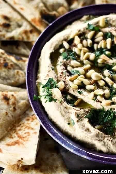 Celebration Hummus 2 Party Hummus, a rich and velvety homemade dip served warm with olive oil, pine nuts, and za'atar. The best hummus recipe.