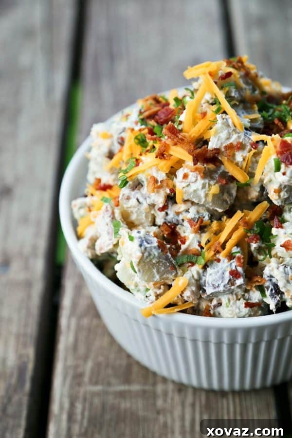 Ultimate Baked Potato Salad 3 Close-up of a serving of Loaded Baked Potato Salad, showing the creamy texture, bacon bits, and cheddar cheese.