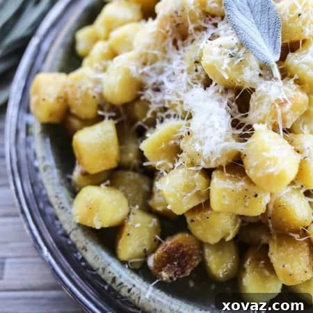 Pillowy Garlic Butter Gnocchi 4 A plate of freshly cooked Garlic Butter Gnocchi with melted cheese and sage garnish.