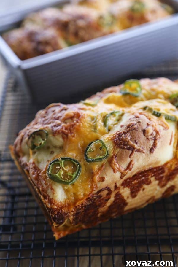 Perfectly golden-brown Jalapeno Cheddar Bread, showcasing its tender texture, fresh jalapeno slices, and melted cheddar cheese, topped with a crispy layer of toasted cheddar.
