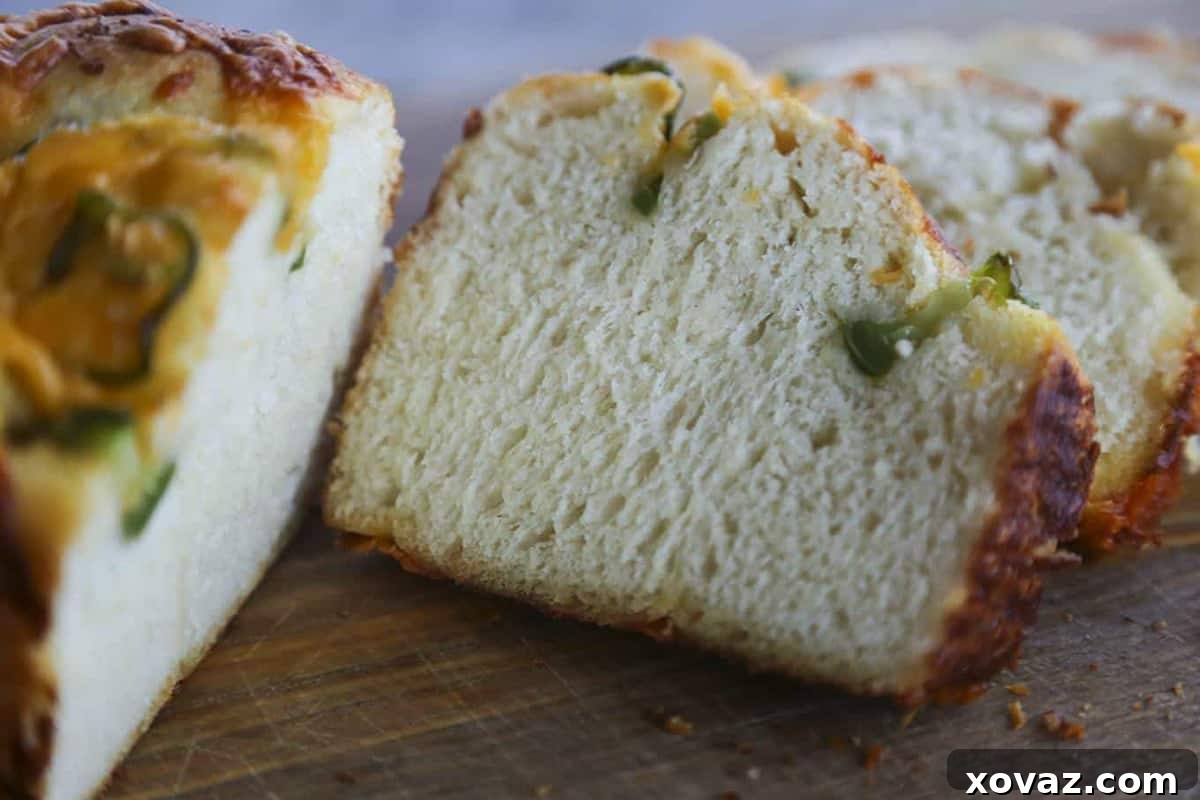 The finished Jalapeno Cheddar Bread, sliced and ready to serve, highlighting its fluffy interior, the vibrant green of the jalapenos, and pockets of melted cheddar.