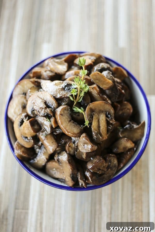 A close-up of savory, tender, umami-packed Garlic Butter Sautéed Mushrooms, glistening with butter and fresh thyme, ready to be served.