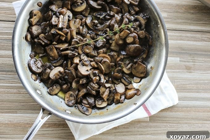 A closer view of Garlic Butter Sautéed Mushrooms arranged on a plate, highlighting their golden-brown color and the flecks of fresh thyme.