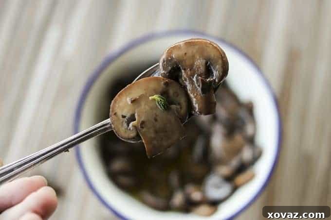 Close-up of golden-brown Garlic Butter Sautéed Mushrooms garnished with fresh thyme leaves, ready to be dished out.