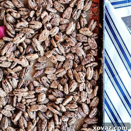Candied Maple Pecans on a silpat lined antique metal sheet pan, crisp blue and white cotton towel, wooden bench