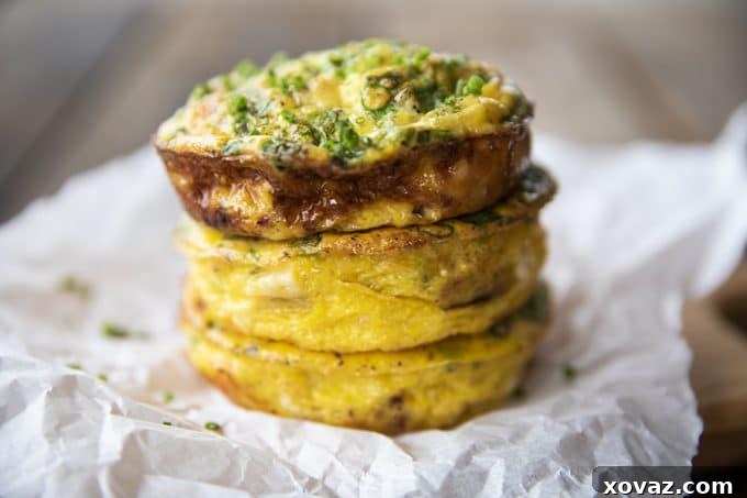 Baked Egg Bites 6 A vibrant selection of Muffin Tin Eggs, featuring crisped Hillshire Farm ham, fresh green onions, and rich cheddar, artfully arranged on a rustic wooden board.