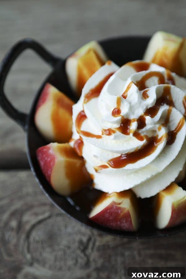 Ultimate Instant Pot Ramen 8 2-Minute Pull Apart Caramel Apples , apple wedges, whipped cream topped with dripping caramel sauce and cinnamon, black and white cast enamel bowl with handles, wooden table