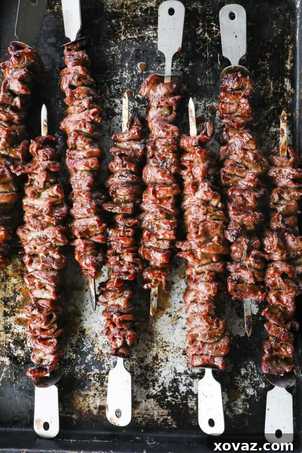 Close-up of perfectly grilled Korean Barbecue Flat Iron Steak slices on skewers, showcasing its smoky, tender appeal.