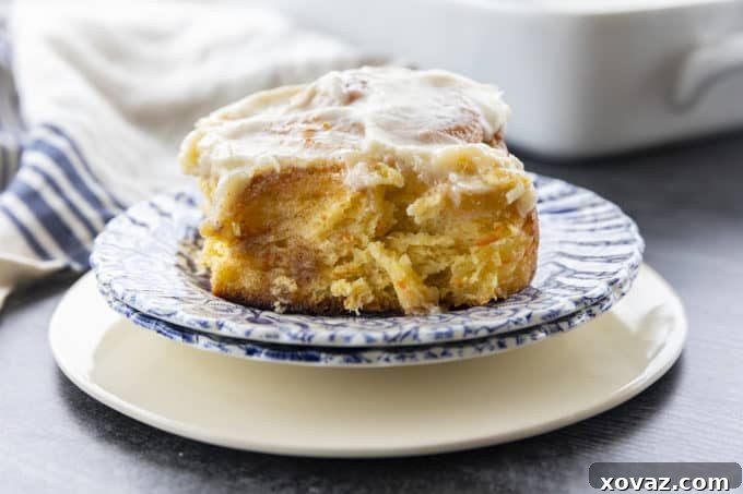 A tray of delectable Carrot Cake Cinnamon Rolls, freshly iced and ready to serve, showing their fluffy texture and generous topping.
