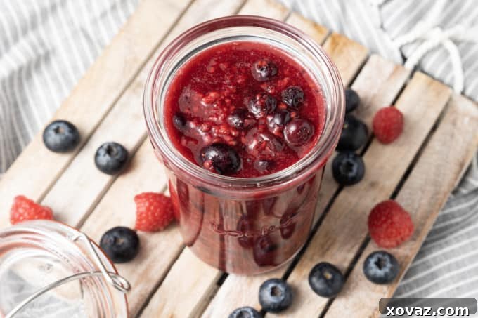 Freshly made berry compote shimmering in a saucepan, with some berries still visibly whole.