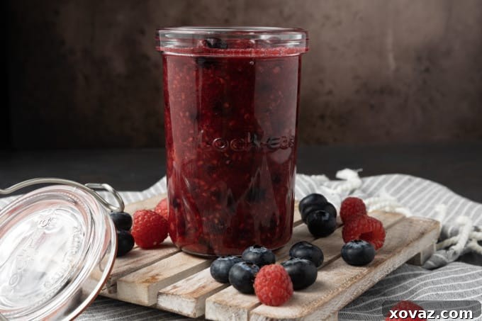 A bowl of freshly cooked berry compote, ready to be served, with a spoon resting in it.