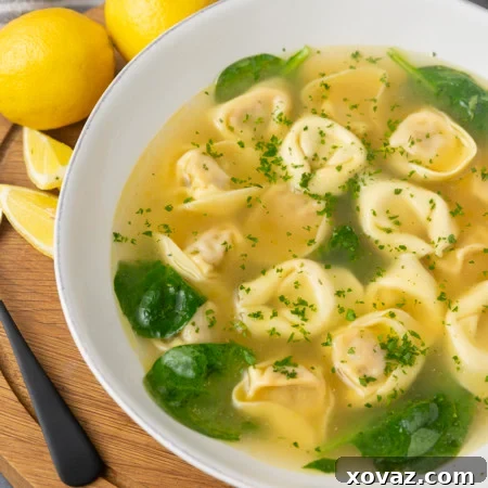 A bowl of Tortellini in Brodo, garnished with fresh herbs.