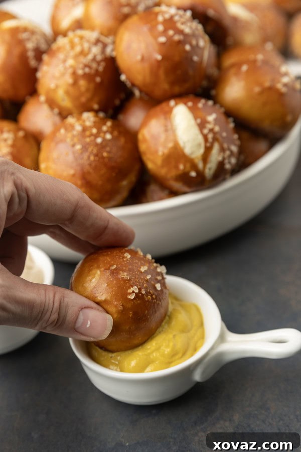 Tangy Sourdough Pretzel Bites 3 A hand dipping a sourdough discard pretzel bite into mustard.