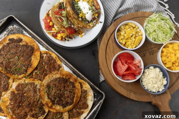 Crispy Smash Tacos 3 Several smash tacos cooking on a hot griddle, with a plate of finished tacos and fresh toppings in the background.