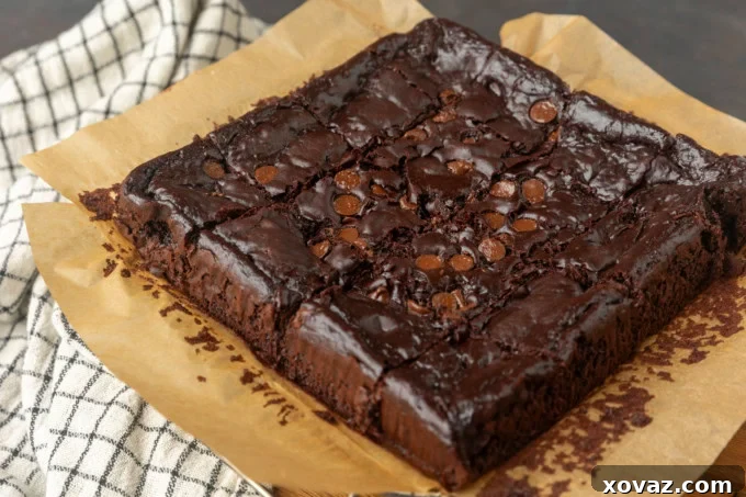 Close-up of baked Greek yogurt brownies on parchment paper, highlighting their rich, dark color and subtle cracks on the surface—a sign of perfect fudginess.