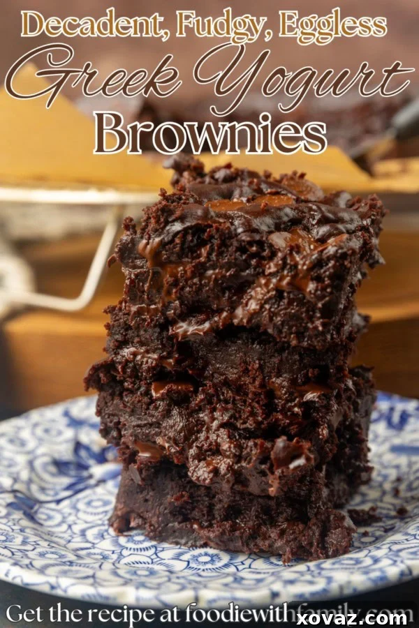 A stack of perfectly cut Greek yogurt brownies, showcasing their thick, fudgy center and a light dusting of cocoa powder, accompanied by a description of their deliciousness.