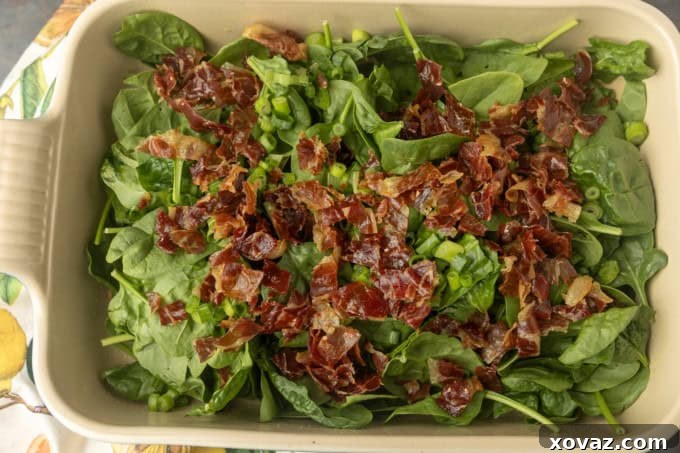 Fresh spinach and crispy prosciutto prepared in a pan, ready for the high protein egg bake mixture.