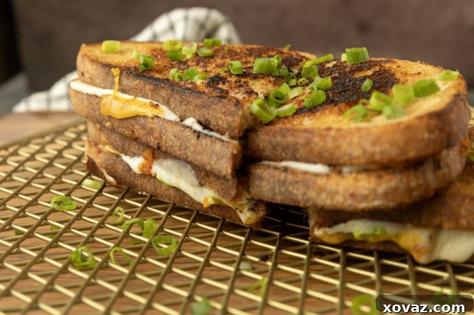 A perfectly golden-brown kimchi grilled cheese, cut in half, with cheese oozing out.