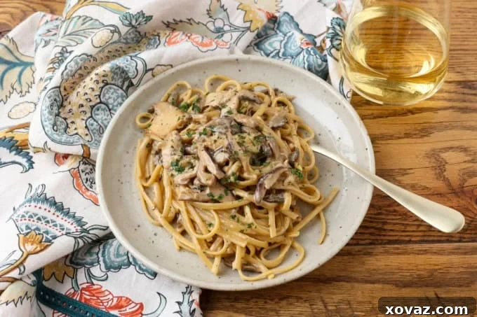 miso mushroom pasta with a fork on a plate with a glass of white wine