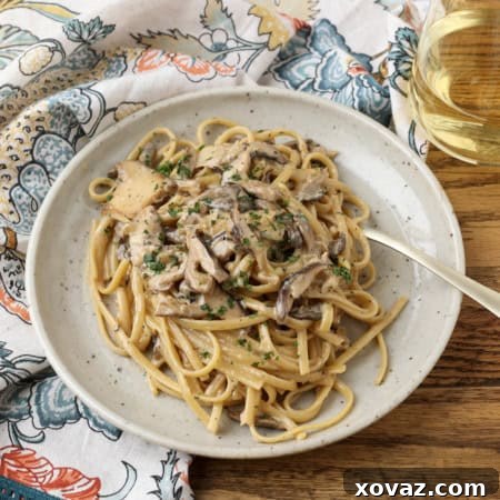 miso mushroom pasta with a fork on a plate with a glass of white wine