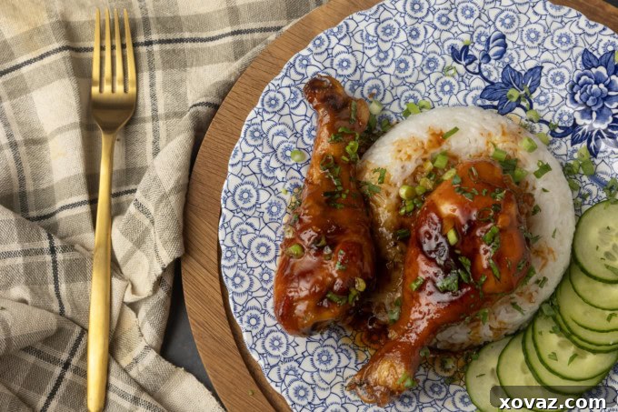 Honey-Glazed Garlic Chicken 3 baked honey garlic chicken on rice with cucumbers on a blue and white plate