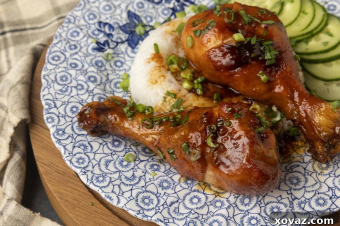 Honey-Glazed Garlic Chicken 4 baked honey garlic chicken on rice with cucumbers on a blue and white plate