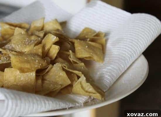 Corn tortilla squares frying to a golden crisp in a skillet.
