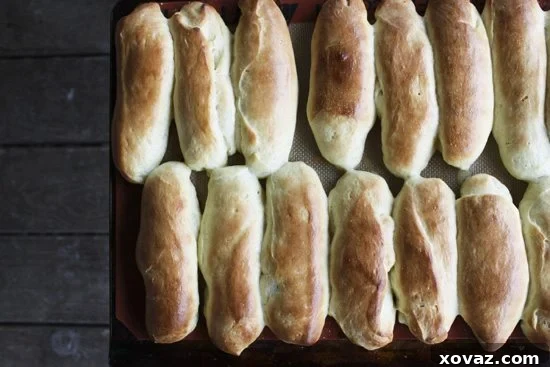 Freshly baked homemade hot dog buns, golden brown and perfectly shaped, arranged on a cooling rack.