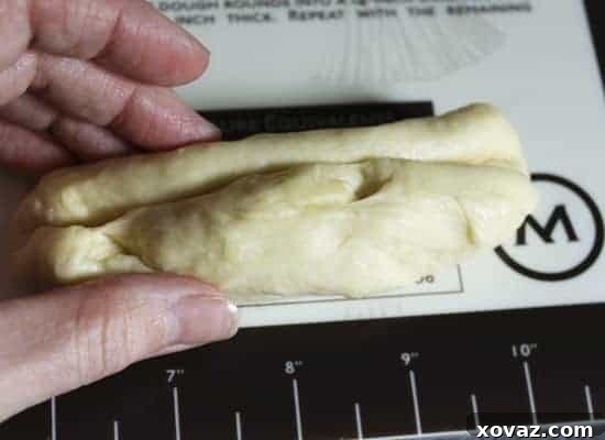 The seam of the rolled dough being lightly pinched closed and sealed.