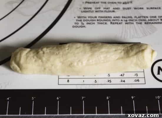 Final shaped hot dog bun dough, rolled to approximately six inches in length with neat, tucked ends.