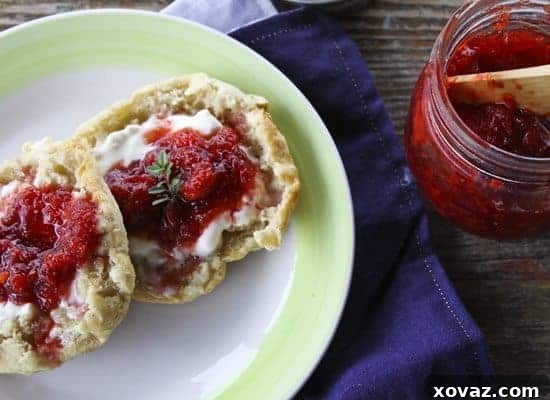 Homemade Strawberry Balsamic Thyme Freezer Jam in a jar, surrounded by fresh strawberries and thyme sprigs.