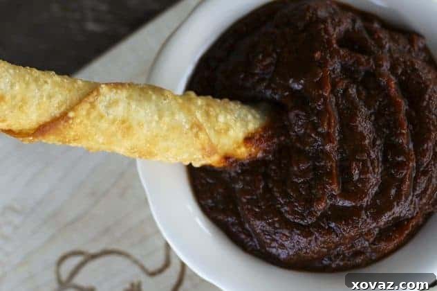 A close-up of freshly fried mozzarella sticks, showing the golden-brown crispy exterior and a long, satisfying cheese pull, with a dipping bowl of marinara sauce in the background.