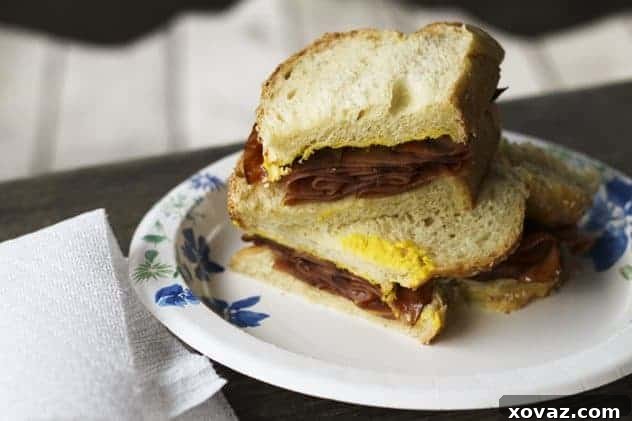 Classic Fried Bologna Sandwich with vibrant yellow mustard on soft white bread, sliced in half.