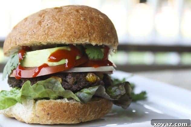 Delicious Taco Black Bean Burger, topped with fresh avocado, lettuce, and hot sauce, served on a soft bun.