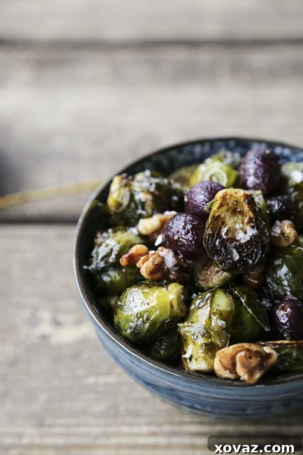 A serving of roasted Brussels sprouts with grapes and walnuts in a dish, ready to be enjoyed, from foodiewithfamily.com