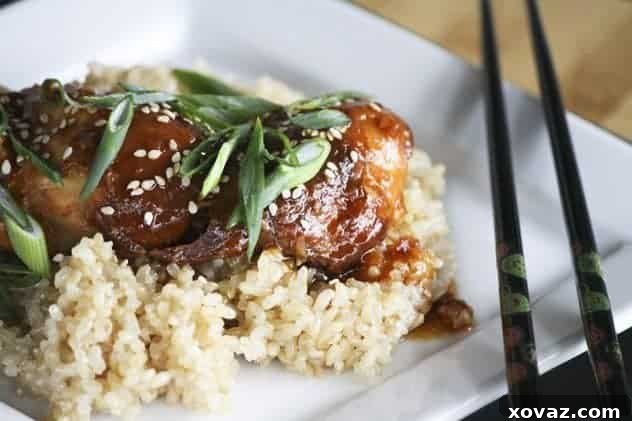 Slow Cooker Honey Sesame Chicken plated over rice, garnished with sesame seeds.