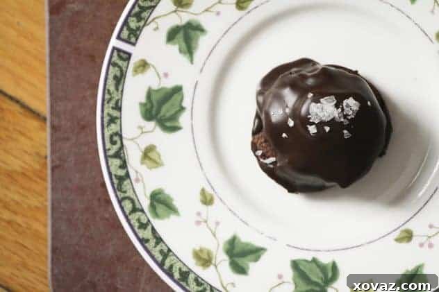 Close-up of a finished Almond Joy or Mounds cookie, showing the layers of chocolate cookie, coconut caramel, toasted almond, and chocolate coating with sea salt.