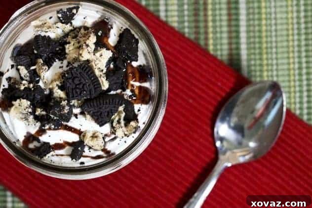 Two jars filled with Chocolate Peanut Butter Whippy Dips, topped generously with whipped cream, chocolate syrup, and crumbled Oreos, ready to be enjoyed.