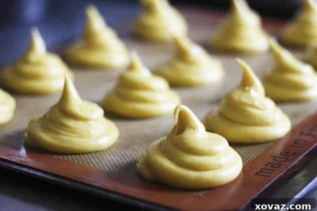 Piped choux pastry dough ready for baking or freezing, showing the precise shapes for cream puffs.