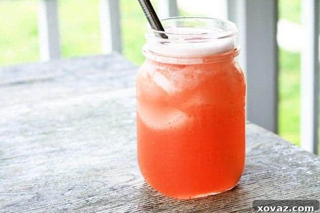 A refreshing glass of Strawberry Wineade with ice and fresh strawberries, perfect for summer.