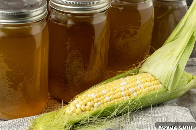 Harvested Bounty 2 Freshly made corn stock in a clear glass jar, with an ear of sweet corn resting beside it, highlighting the vibrant color and natural origin of the stock.
