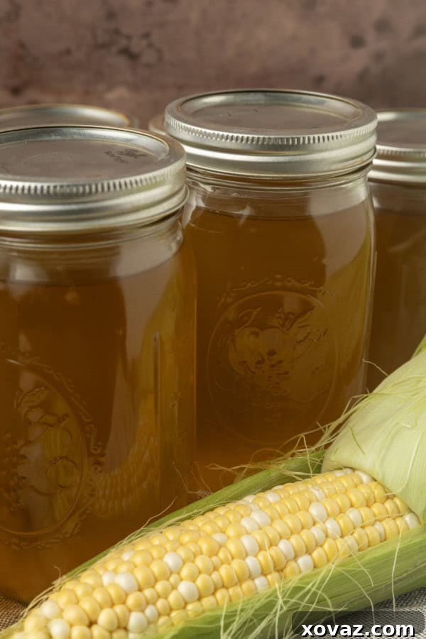 Harvested Bounty 6 A jar of homemade corn stock with an ear of sweet corn, ready for storage or immediate use in various recipes.