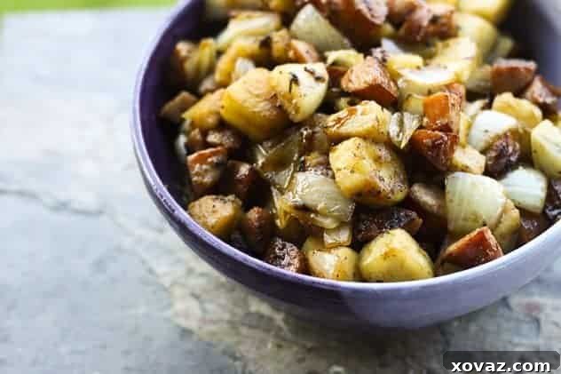 A hearty serving of Kielbasa, Apple, and Onion Stir-Fry atop golden mini puff pancakes, garnished with fresh herbs, ready to be enjoyed.