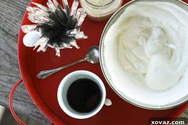 Close-up of a Peppermint Mocha being garnished with whipped cream and peppermint stick in a mug.
