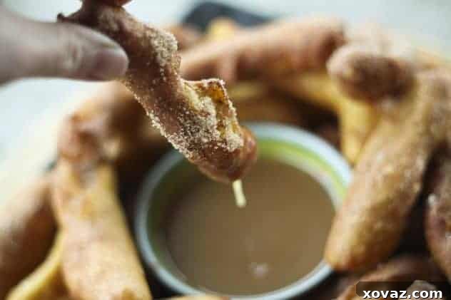 Close-up of a Banana Churro being dipped into rich Butter Rum Caramel sauce