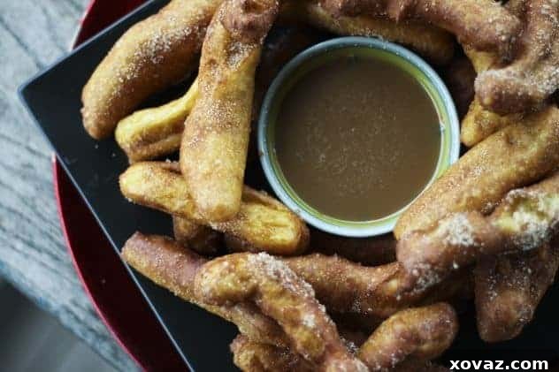 A plate of golden Banana Churros with a bowl of Butter Rum Caramel dipping sauce