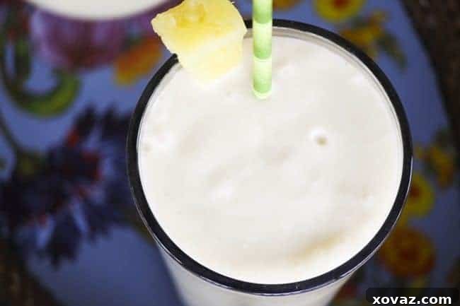 Tropical Vegan Piña Colada Bliss 3 A refreshing Piña Colada Smoothie in a glass, garnished with a pineapple slice.